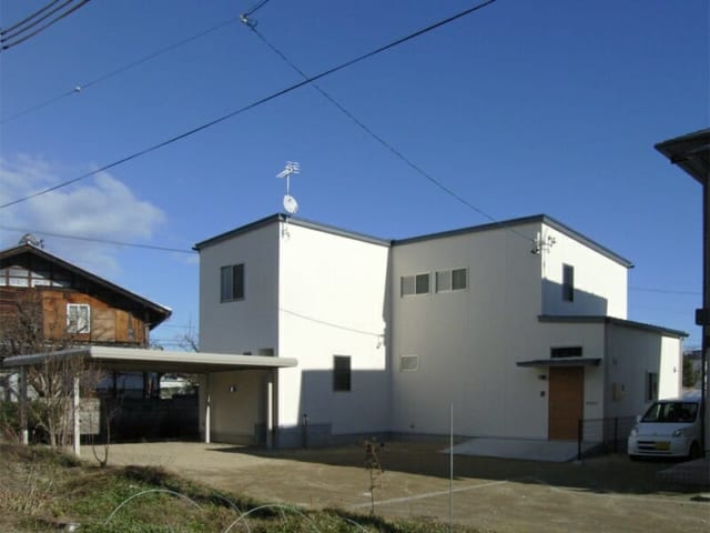 青い空に映える白い外観。壁は白いジョリパット吹付け、屋根にはガルバニウム鋼板を使用した