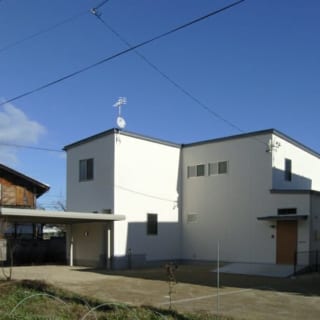 青い空に映える白い外観。壁は白いジョリパット吹付け、屋根にはガルバニウム鋼板を使用した