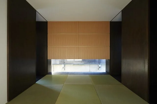 １階　和室／写真正面のタモ材を使用した大きな造り付け収納の明るい色合いを、壁面のダークブラウンが引き締め洗練された印象。縁のない琉球畳を選び、よりオリエンタルな雰囲気になっている。 窓越しには公園のフェンスで圧迫感があるため、窓は低く配置した