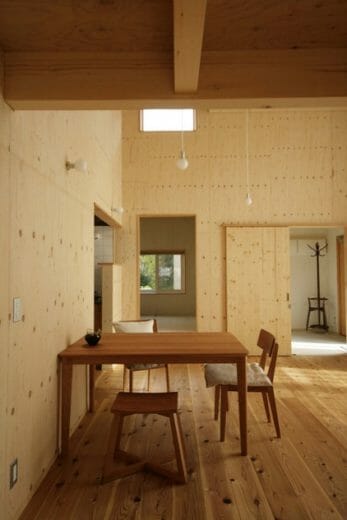 　リビングダイニングから、玄関や和室を望む。全ての居室が一続きとなったワンルームのような空間を創出しながら、高低差や色のバランスを取ることで、視覚的な変化が楽しめる。家具も及川さんが提案。赤みがかった木肌が美しい、レッドチェリーのダイニングテーブルや椅子を配置し、様々な樹種が共存する空間にリズムを生んでいる