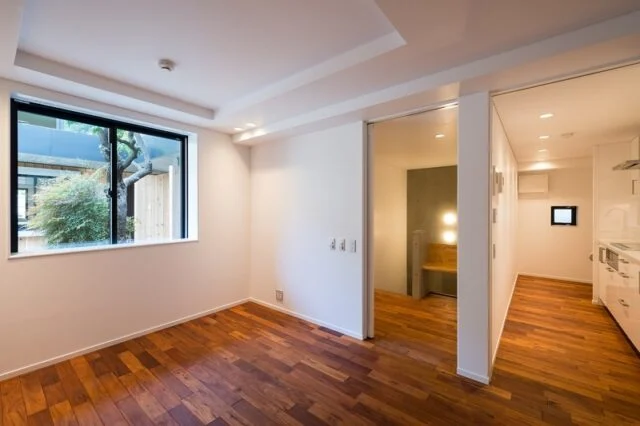 賃貸住戸　居室～キッチン／メゾネットタイプの住戸。写真右は料理が楽しみになりそうな、ゆったりとしたキッチン。写真中央のコンクリート打ち放し部分は階段で、下りると居室、バスルームといったプライベート空間がある