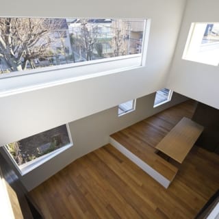 吹き抜け／寝室はLDKから数段上がったロフト部分。滝口さんはこの視線の高さに合わせて壁一面に大きく広がる窓を配置した。朝日も差し込み、とても気持ちのいい目覚めができそう。日々変化する公園の落葉樹の様子を存分に楽しみながら、四季を感じることができる