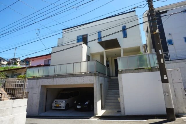 地盤がかたく、掘るのが大変だったという駐車場。駐車場から階段の方へ出る入り口にはドアの下にステップが1段ある。コストを下げるために角張ったかたちにしていたステップを、職人さんが「危ないから」と手間を惜しまず好意で丸みのついた安全なかたちにしてくれた