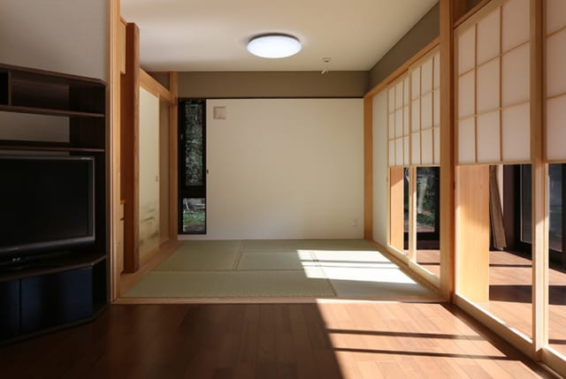 1階　縁側～茶の間・窓／縁側突き当りのガラスや茶の間の縦長の窓は、視線が抜けて開放感を与える役割を持つ。これなら仕切りを閉じて部屋を利用する際も圧迫感を感じることがない