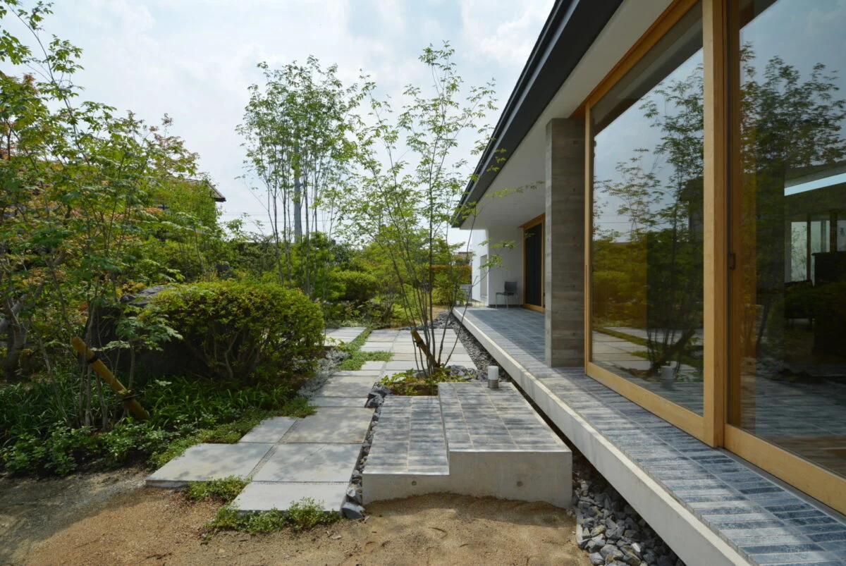 客間と玄関側より。玄関然としない仕上がりを狙った。上がり口となるタイルの階段が目印。庭への動線には砂岩を敷いた