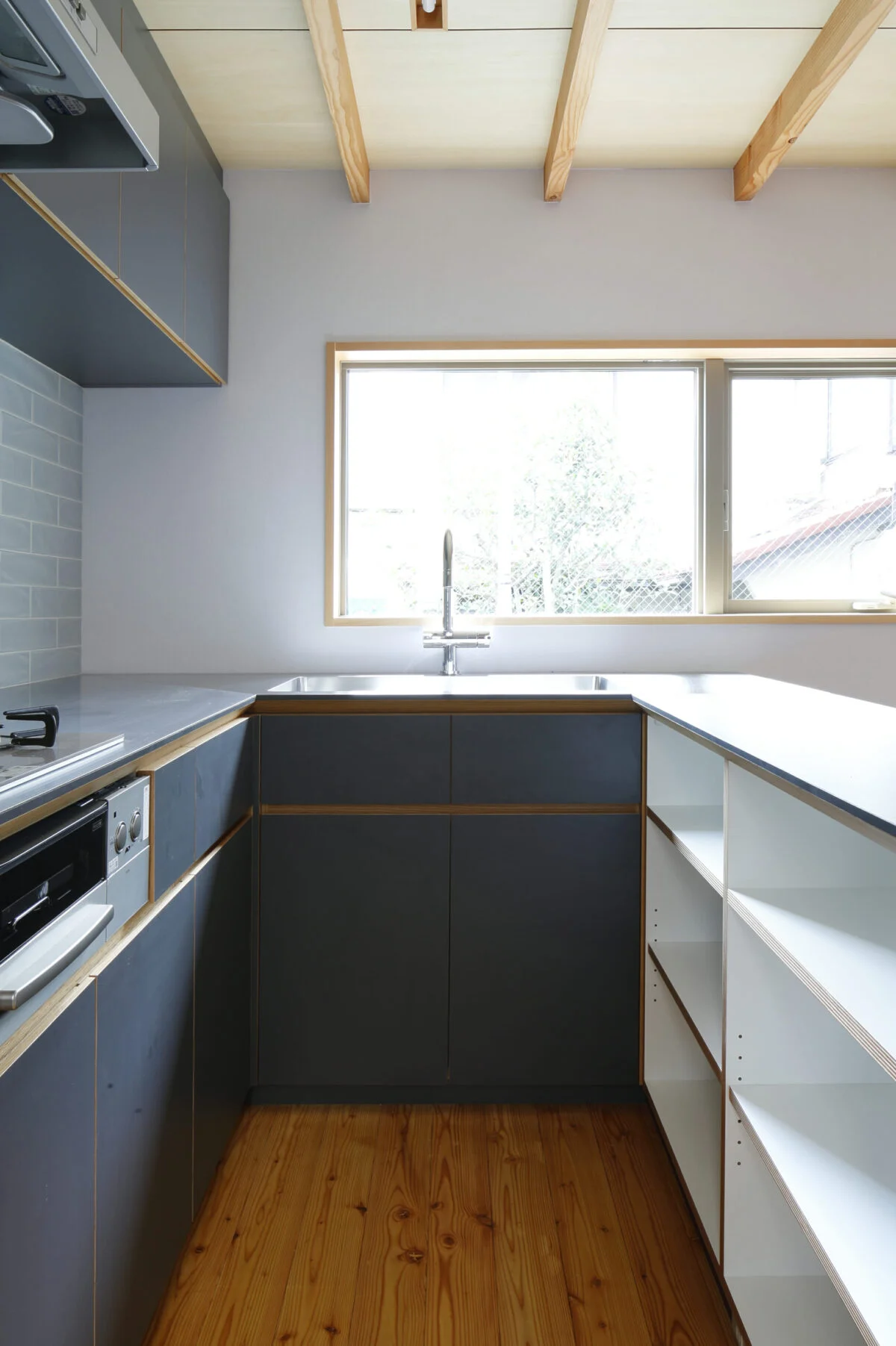 建物全体にも使用しているキーカラーのブルーグレーを使用。食器棚はオープンにしてコストダウンをはかった