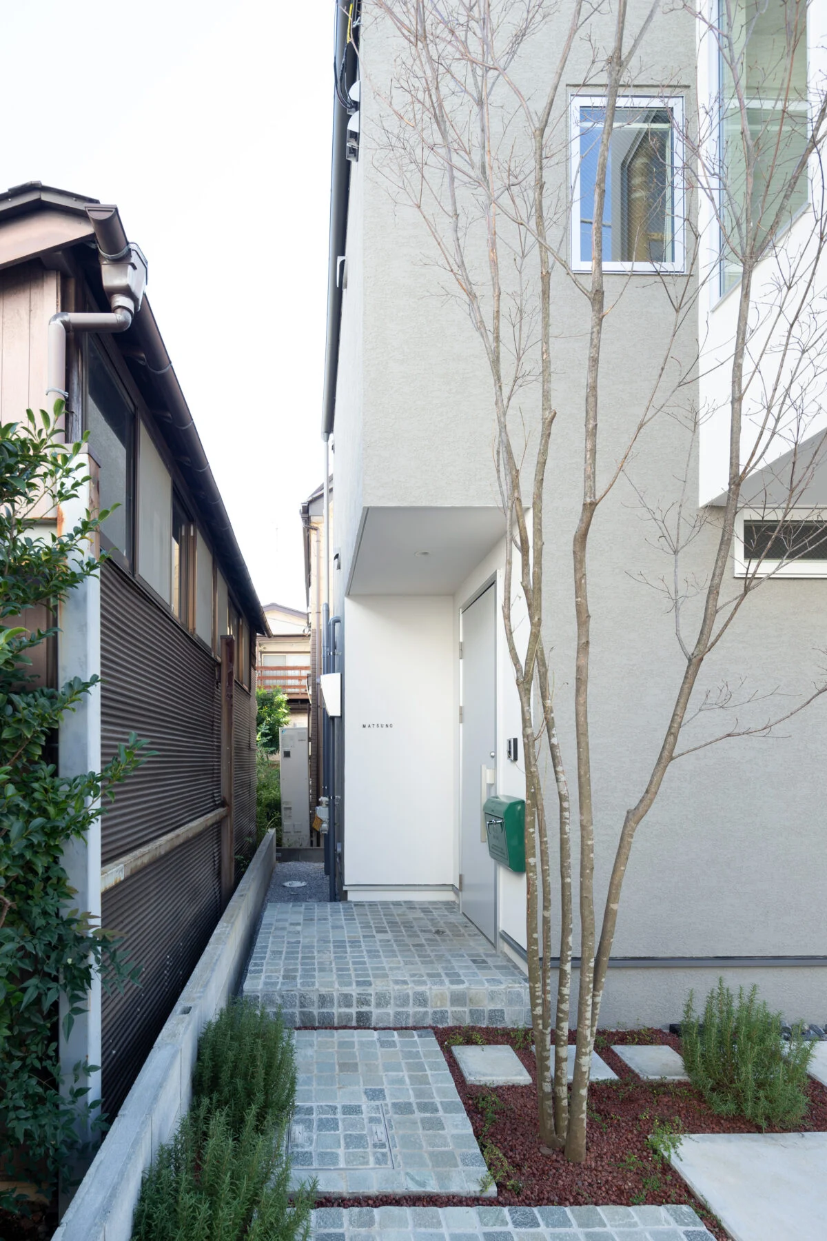 玄関へのアプローチは小さな石を張り、石畳風に仕上げた。シンボルツリーはかわいい花が咲くヤマボウシ