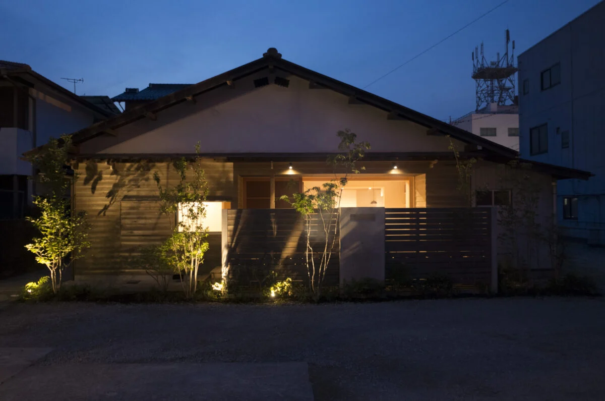 外観夕景。植込みやウッドデッキの軒に配した照明の光がやさしく広がり、美しい佇まいを見せる