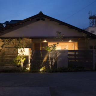 外観夕景。植込みやウッドデッキの軒に配した照明の光がやさしく広がり、美しい佇まいを見せる