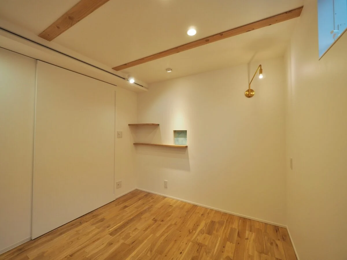 1階のMさまの個室は、天井の梁を出して表情をつけた。写真右の照明はMさまのセレクト。吉田さんはこの照明とのバランスを考え、写真左上部にさりげなくレール照明を設置。写真奥の小さな曇りガラスの窓は玄関のニッチ棚とつながっていて、ほのかに明かりが漏れて気配がわかる
