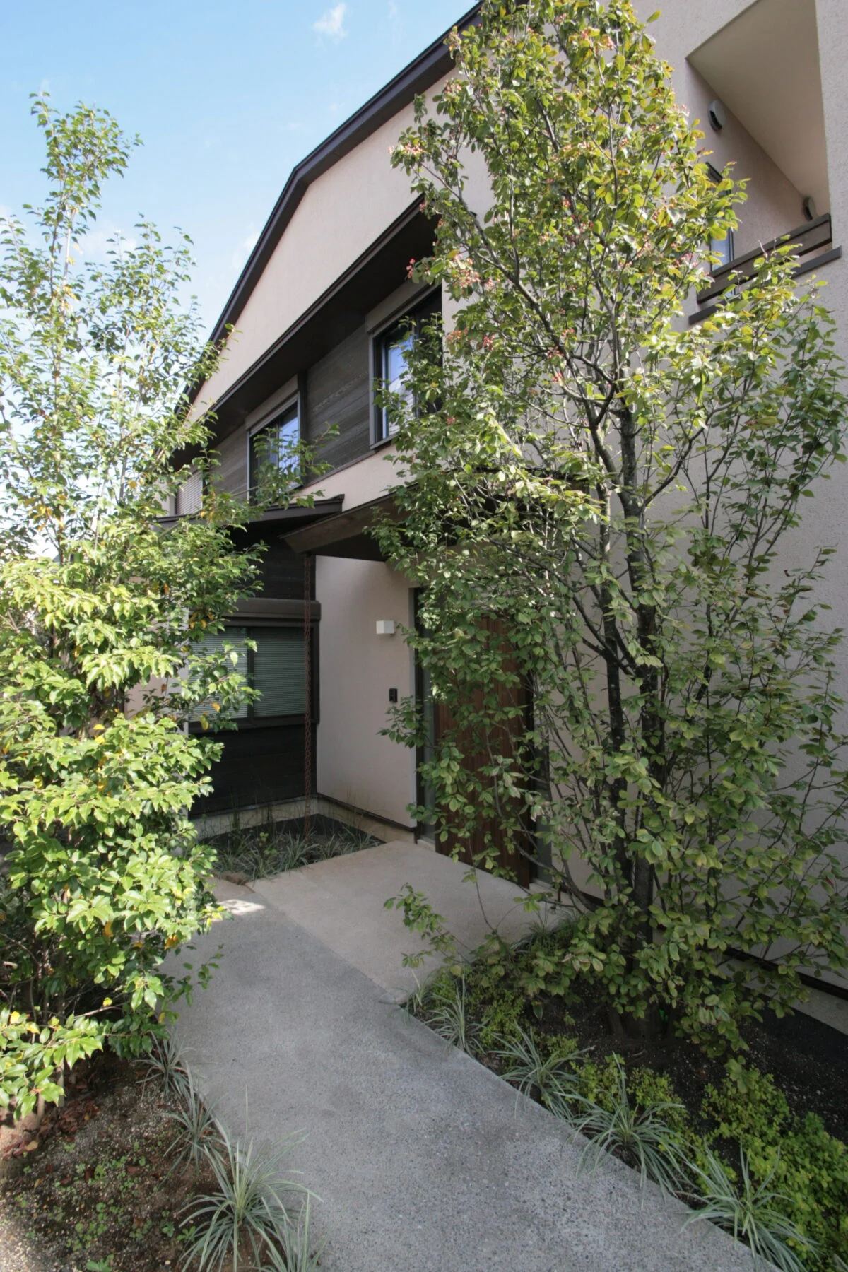 玄関へのアプローチ。建物をL字に凹ませてできた余白を前庭にすることで、旗竿地でもゆとりを感じる造りに