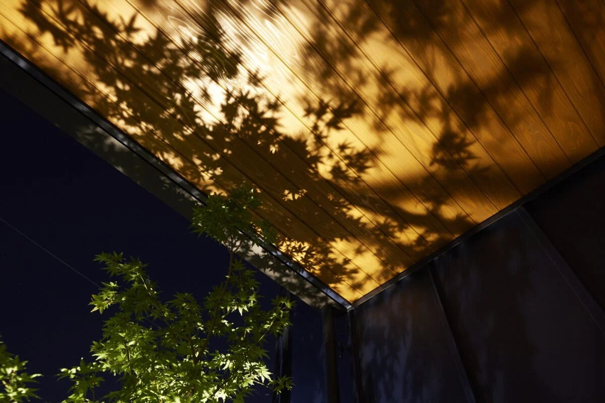 玄関ポーチにはお子さまにちなんだ樹木を植えている。根元には照明があり、夜は板張りの軒天に木の葉の美しいシルエットが浮かぶ。「生きている木の影を、木に映す」という遊び心が楽しい