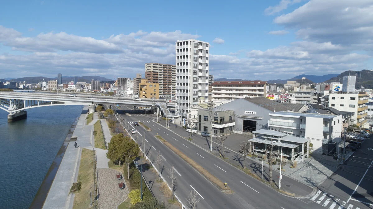 写真右手前、海沿いにあるカフェは街並みに馴染みつつも存在感を放つ。角地にあり道路と2面で接しているため、あえてどこからでも敷地に入れるような雰囲気をつくった。海側の植栽は店内から外を眺める人だけでなく、道行く人の目も楽しませている