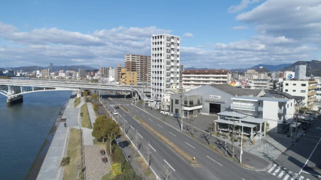 写真右手前、海沿いにあるカフェは街並みに馴染みつつも存在感を放つ。角地にあり道路と2面で接しているため、あえてどこからでも敷地に入れるような雰囲気をつくった。海側の植栽は店内から外を眺める人だけでなく、道行く人の目も楽しませている