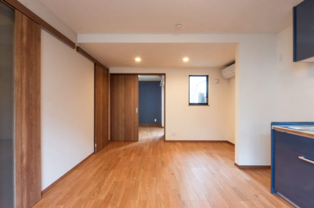 1階賃貸A住戸、LDKから寝室までを見る。一続きになった空間は道路側にリビング、奥に寝室を配置し、騒音も考慮した。道路側にある窓に加えて、写真正面の窓からもテラスを通して光が入るためLDKはいつでも明るい。寝室からはテラスに出ることもできる