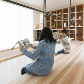 2階吹き抜け。廊下として使うホールも、ちょっとしたテーブルのように使える板を設けることで、空間の使い道がぐんと広がる。奥の本棚が壁がわりとなって、プライベートな空間である寝室を仕切る