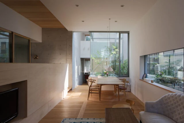 【A住戸】奥行きのある住空間の中ほどに中庭を設けた住戸（写真中央）。屋外の自然を間近に感じて暮らせる落ち着いた空間だ。リビング・ダイニングは床が地面より低いため、椅子に座ると緑が迫るように目に入る