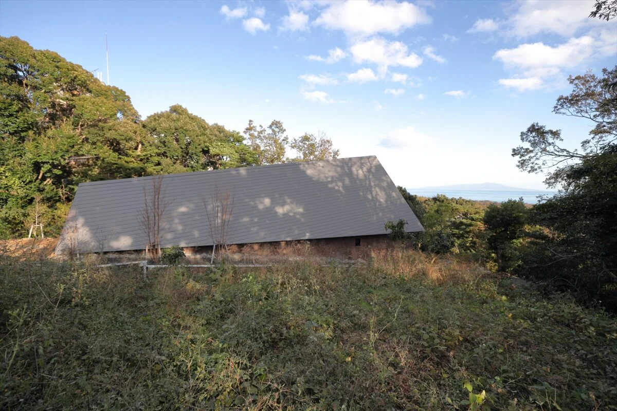 道路側からはほぼ家の屋根のみが見え、プライバシーを確保。画像左側にある玄関から海に向かって屋根が上がり、内部空間も同じように広がっていく