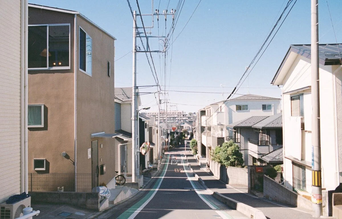 外観。写真左のブラウンの外壁の住宅がhouseA。ならだかに傾斜した住宅街の一角に立つ