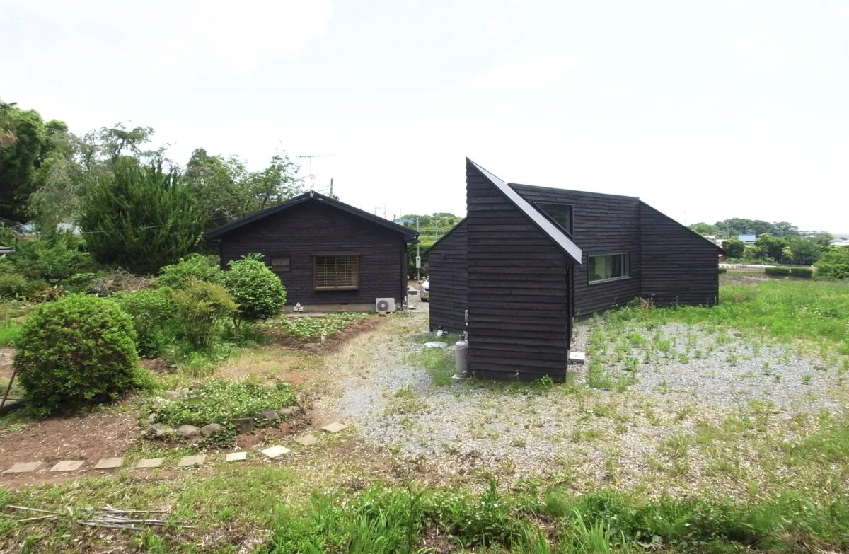 焼杉の外壁をお気に召されたお施主のS様は、隣接するご両親宅の外壁にも焼杉を貼ることにされた。同じ外観の雰囲気を持つ家が並び、一帯の風景がさらに魅力的なものになった。竣工時は畑との境界がはっきりと分かれていたが、少しずつ自然が浸食し今は曖昧になっている