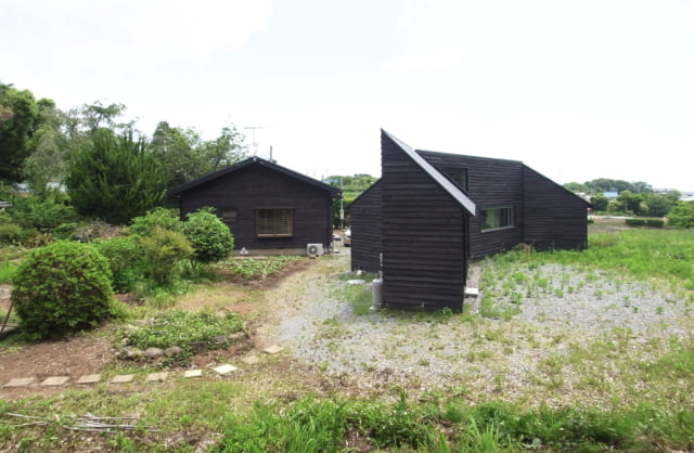 焼杉の外壁をお気に召されたお施主のS様は、隣接するご両親宅の外壁にも焼杉を貼ることにされた。同じ外観の雰囲気を持つ家が並び、一帯の風景がさらに魅力的なものになった。竣工時は畑との境界がはっきりと分かれていたが、少しずつ自然が浸食し今は曖昧になっている