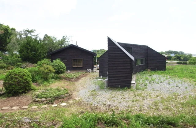 焼杉の外壁をお気に召されたお施主のS様は、隣接するご両親宅の外壁にも焼杉を貼ることにされた。同じ外観の雰囲気を持つ家が並び、一帯の風景がさらに魅力的なものになった。竣工時は畑との境界がはっきりと分かれていたが、少しずつ自然が浸食し今は曖昧になっている