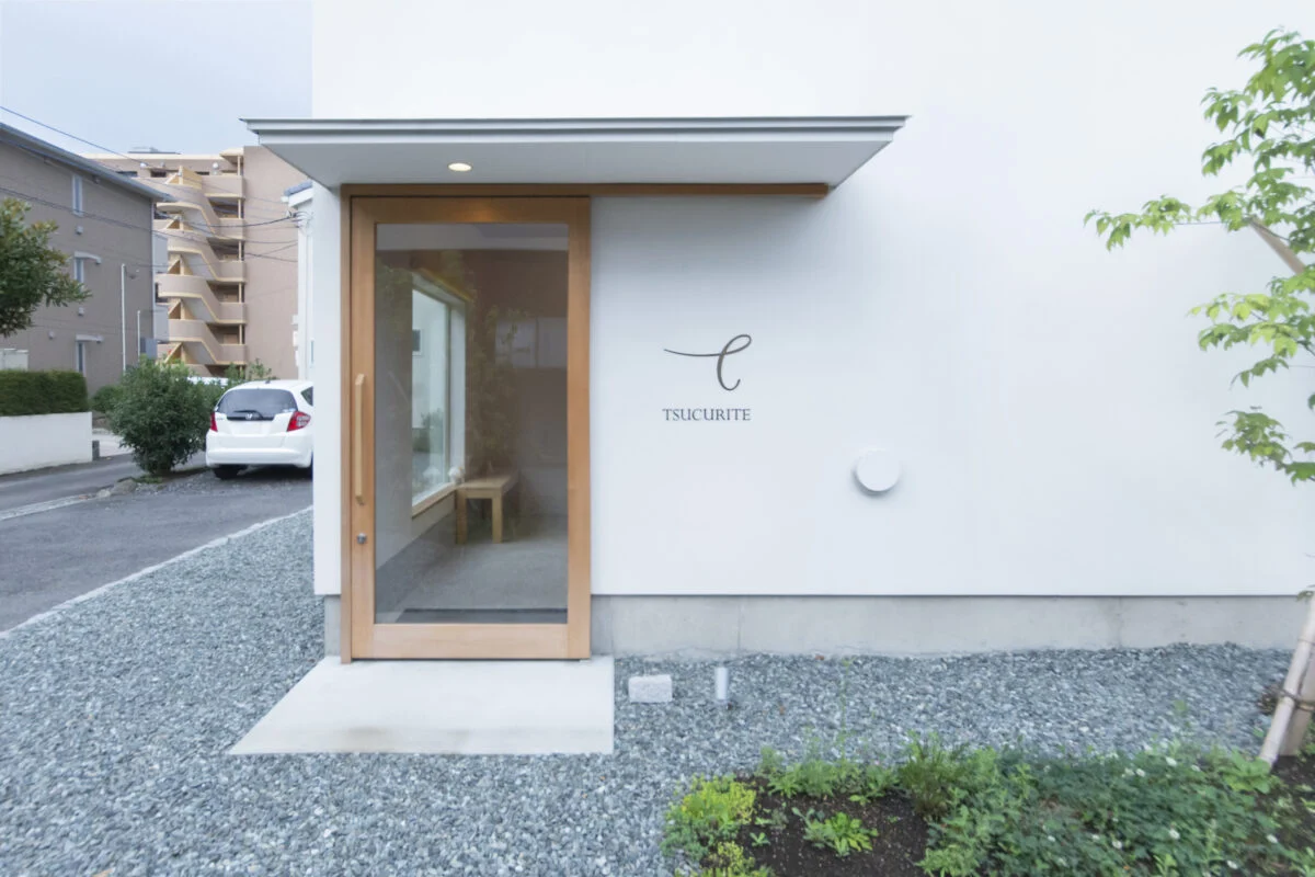 店舗入口は木製のガラスドア。店内が見えて心理的に入りやすく、やさしげな木の温かみにも心が和む。東面（写真左）の奥には自邸への玄関がある