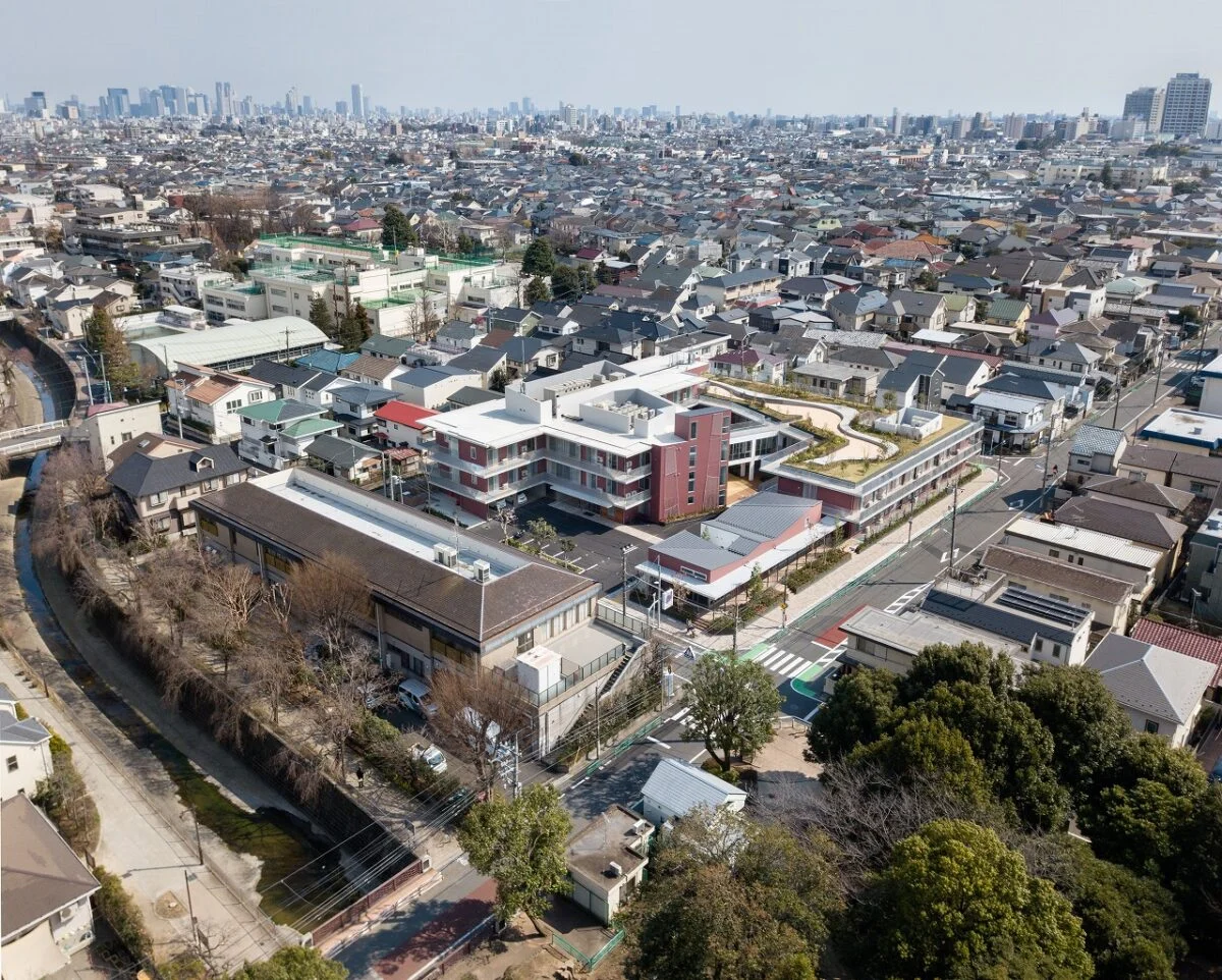 上空からの眺め。写真中央、広々とした屋上庭園のあるレンガ色の建物が『リバービレッジ杉並』。写真右手前の緑が妙正寺公園。左手前が妙正寺川。周辺は、緑に包まれた低層の住宅地