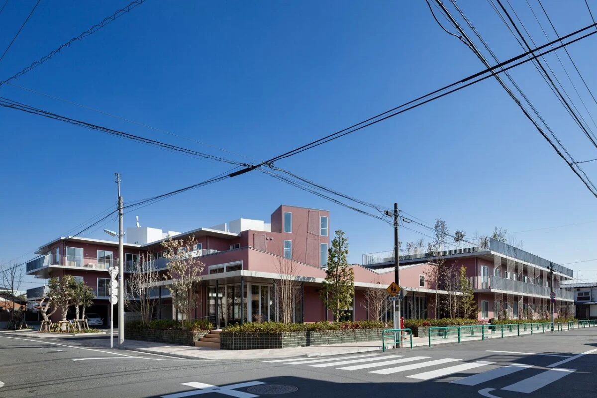 交差点から見た外観。屋上庭園の樹木には、道路からも緑が見える背の高い木々もある。外壁は緑が映えるレンガ色。建物全体が生き生きとした緑に彩られ、街の景観をよりよいものにしている