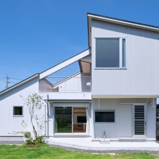 東側の庭から見た外観。物干し場の上がオーバーハングになり、2階部分の建物の中央に広々としたオープンエアのバルコニーを配置