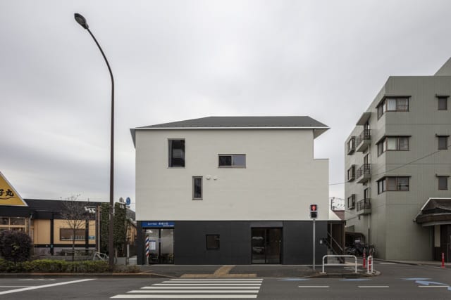北側、幹線道路から光が丘の家を眺める。店舗やマンションなど、周りの建物とボリュームを合わせ見劣りしないような外観をつくりあげた。テナントが入る1階部分と、2、3階の住居部分とは外壁の色を反転させて視覚的にはっきり分け、それぞれの独立性を高めた