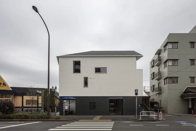 北側、幹線道路から光が丘の家を眺める。店舗やマンションなど、周りの建物とボリュームを合わせ見劣りしないような外観をつくりあげた。テナントが入る1階部分と、2、3階の住居部分とは外壁の色を反転させて視覚的にはっきり分け、それぞれの独立性を高めた