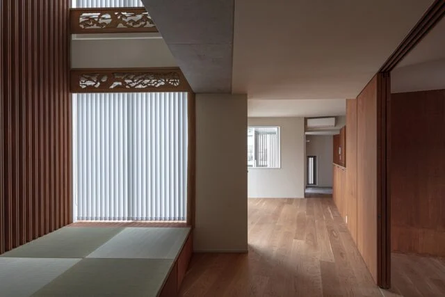 2階、水回り空間へ続くドアの前から玄関方向を見る。家の奥から玄関まで一直線に視線が抜け、また効果的な窓の配置により外も見える。日光も豊かに入り、木目が感じられる床や建具と相まって温かな雰囲気の2階。外断熱のため快適温度が保ちやすく、一日気持ちよく過ごせる