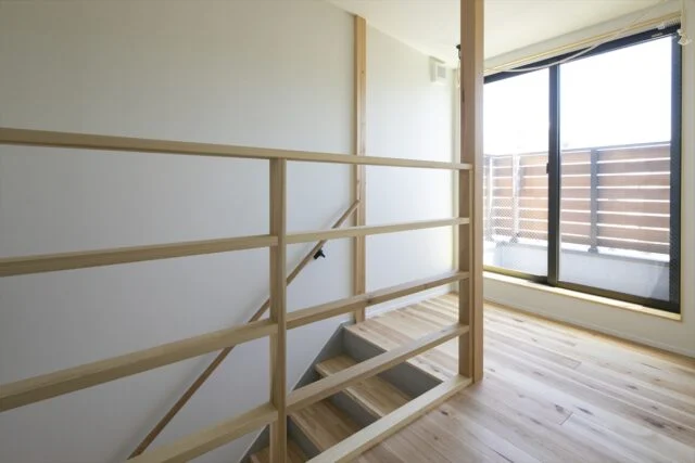 ３階への階段正面には大きな窓が。南からの陽光を下階へと導いている。天井のロープは、物干しとしての活用も可能