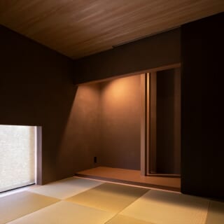 親族の宿泊などに使える和室。内装の色のトーンを落としてぐっと落ち着いた雰囲気に仕上げている。地窓（写真左下）のロールスクリーンを上げると南の雑木林の緑が見える。Kさまのお子さまはこの窓を開けて腰掛け、絵本やおもちゃで遊んでいるそう