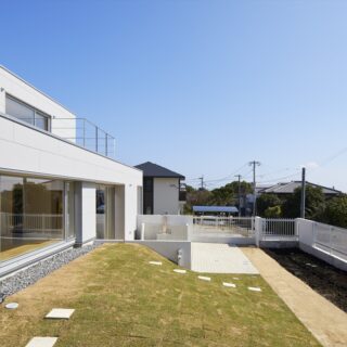 土地の高低差を巧みに利用した、ドッグランを兼ねた庭。芝生の丘のトップは、窓越しに愛犬と視線が合うよう盛り土をして高さを調整。塀際の土のスペースは、小さな菜園として利用しているという
