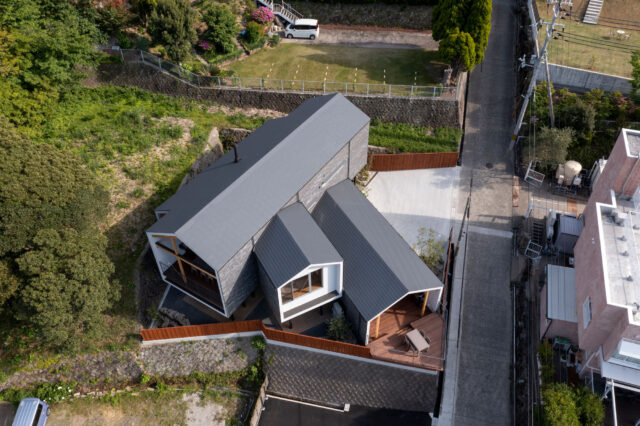 外観。建物は高台に位置する。建物の左には隣地が迫っているが、急斜面のため新しく建物は立たないだろうと判断して購入を決めた。道路を挟んだ向かいには、もう一つの購入の決め手となった食事のおいしいオーベルジュがある
