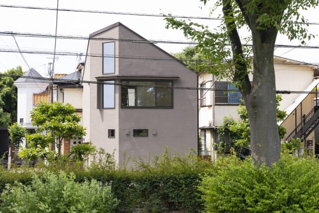 公園から見た外観。左官塗りで仕上げたベージュの外壁が木々や緑とナチュラルに馴染み、まるで公園の一部のような佇まい