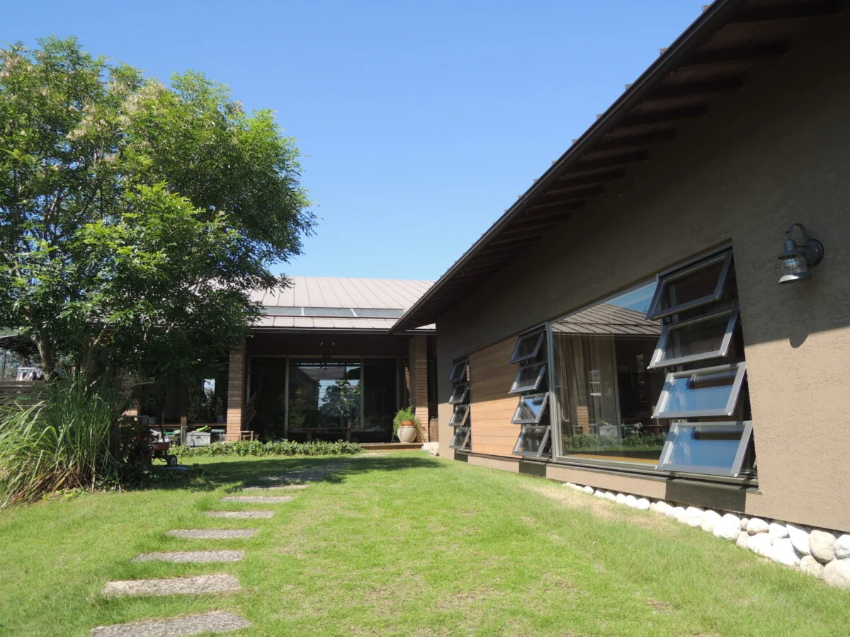 【増築後】写真奥が既存家屋。写真右が既存家屋とL字につながる増築部分。増築部分は敷地の東側に位置し、東隣の住宅からの目線除けを兼ねている。西側は果樹園なので両サイドともにプライバシーが守られ、プライベート感は抜群。敷地全体が、緑に包まれた別世界のよう