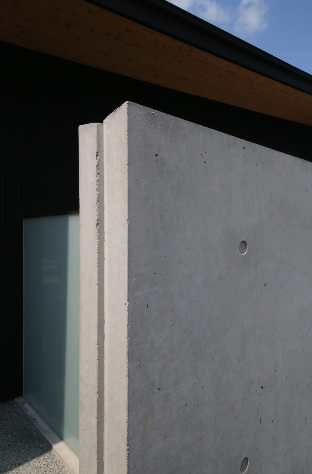コンクリート壁上面に中央部がへこんだ傾斜を設け、側面に切られた溝を伝って雨水が流れ落ちるようになっている