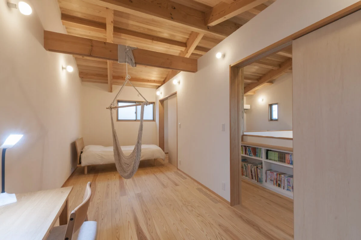 2階子ども室１、２。現在はハンモックを外し、建具を入れて2部屋にした。壁が入りコンパクトな空間になっても、天井が2階全体で繋がっているのがわかるため圧迫感がなく、また安心感を得られる。扉を開ければ、本やおもちゃなどが置いてある子どもスペースまで意識が拡張される

