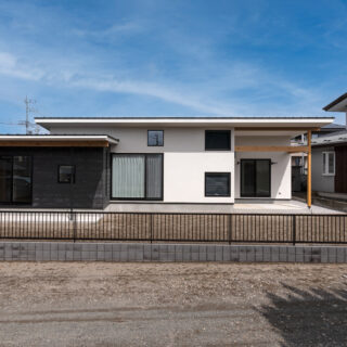 南側からの眺め。左手の茶の外壁部分が子ども部屋と書斎で、白い壁の主棟より少し南へずらしてレイアウトすることで道路から庭が見えにくいようにしている。手前は近隣の生活道路なので、人通りは少ない

