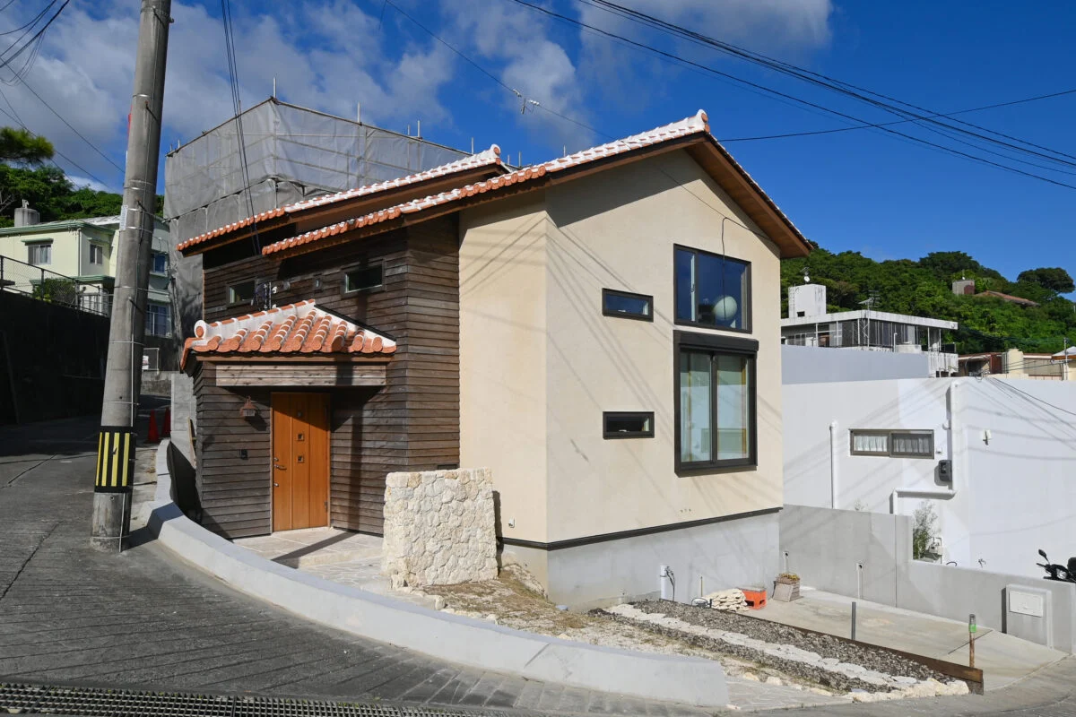 赤瓦の切妻屋根と琉球石灰岩の左官壁が目を引く岸田邸の外観。周りの集落に見事に溶け込むデザインとなっている