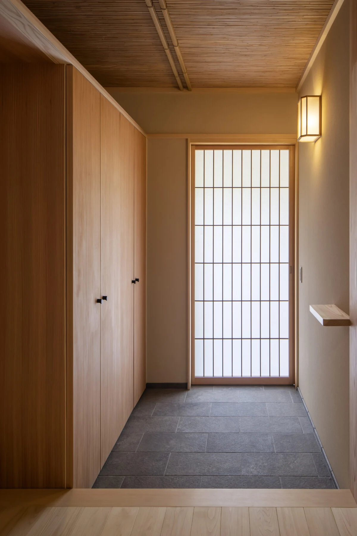 親世帯玄関。玄関扉のほかに障子戸や網戸を重ねて計画。必要ないときは引き込める。天井は葦を使用。美しい