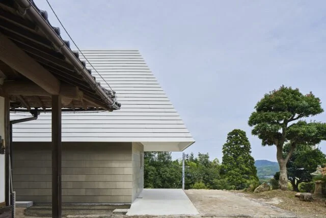 K邸へのアプローチは、母屋の前を通って。深い軒下は、雨に当たらない駐車スペースと作業スペースを生んだ。