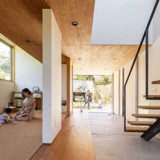 南庭の前から子ども部屋（左）、土間、玄関、前庭までを見る。写真右、階段下に夫婦の寝室への仕切り戸がある。階段のすぐ奥の扉はトイレ、さらに水回りへと続く。子ども室の上部、ラワン合板の天井裏部分には大容量のロフト収納を計画