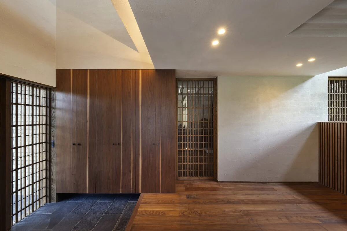 玄関（左）、ホール（右）。正面の仕切り戸はLDKに続く。建具などは既製品を使わず全て造作し、細やかなところまで雰囲気を統一。画像左の収納は奥さまが気に入られたキッチン収納と同じ、白い模様が入ったウォールナット素材を使用した。これも、造作だからこそできたこと