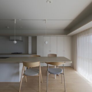 ダイニングキッチン。リノベーションによりキッチンは対面式に変更。シンクからシームレスに続くダイニングテーブルの天板は温もりある左官仕上げに。シンク下はあえて凹ませ、来客時に椅子やベンチを置けるようにした。コンロは壁側。手の届く右側に収納式のスパイスラックを計画