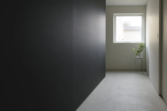 ポーチから玄関に入った場所からの視線。奥は左に向かって主に家族が使用する西側の廊下が続く。土間空間を廊下の一部まで延長し、靴などを壁面の奥に隠せるようにした。右の扉は納戸。収納力もあり、また玄関と接しているおかげで使い勝手がいい
