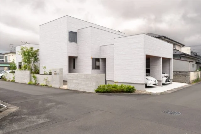 外観。横長に広い土地のため、建物をシンプルにすると圧迫感が出てしまう。そこで建物に変化をつけた。擁壁も高さだけでなく道路との距離を細かく変え、外壁と同じ仕上げにすることで圧迫感がないように工夫した。近隣の方からも好評で、地域のランドマークになっている
